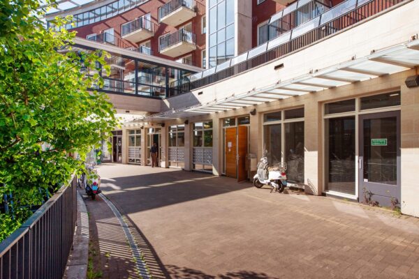 Binnenplein van het Harriet Freezerhof met appartementen, glasoverkapping en scooters bij de entree.